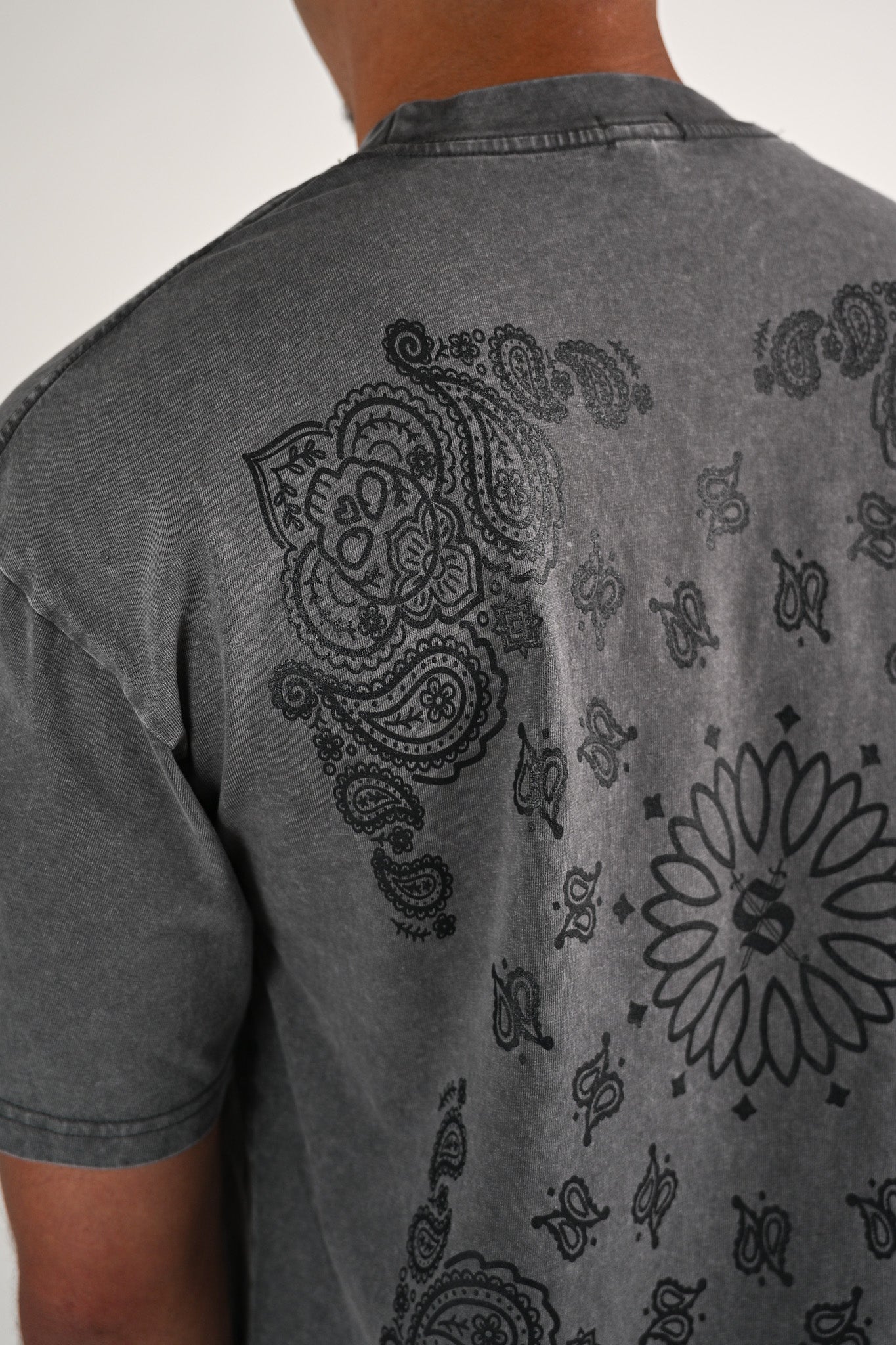 Close up of a gray acid wash t-shirt with a skull bandana paisley design on the back