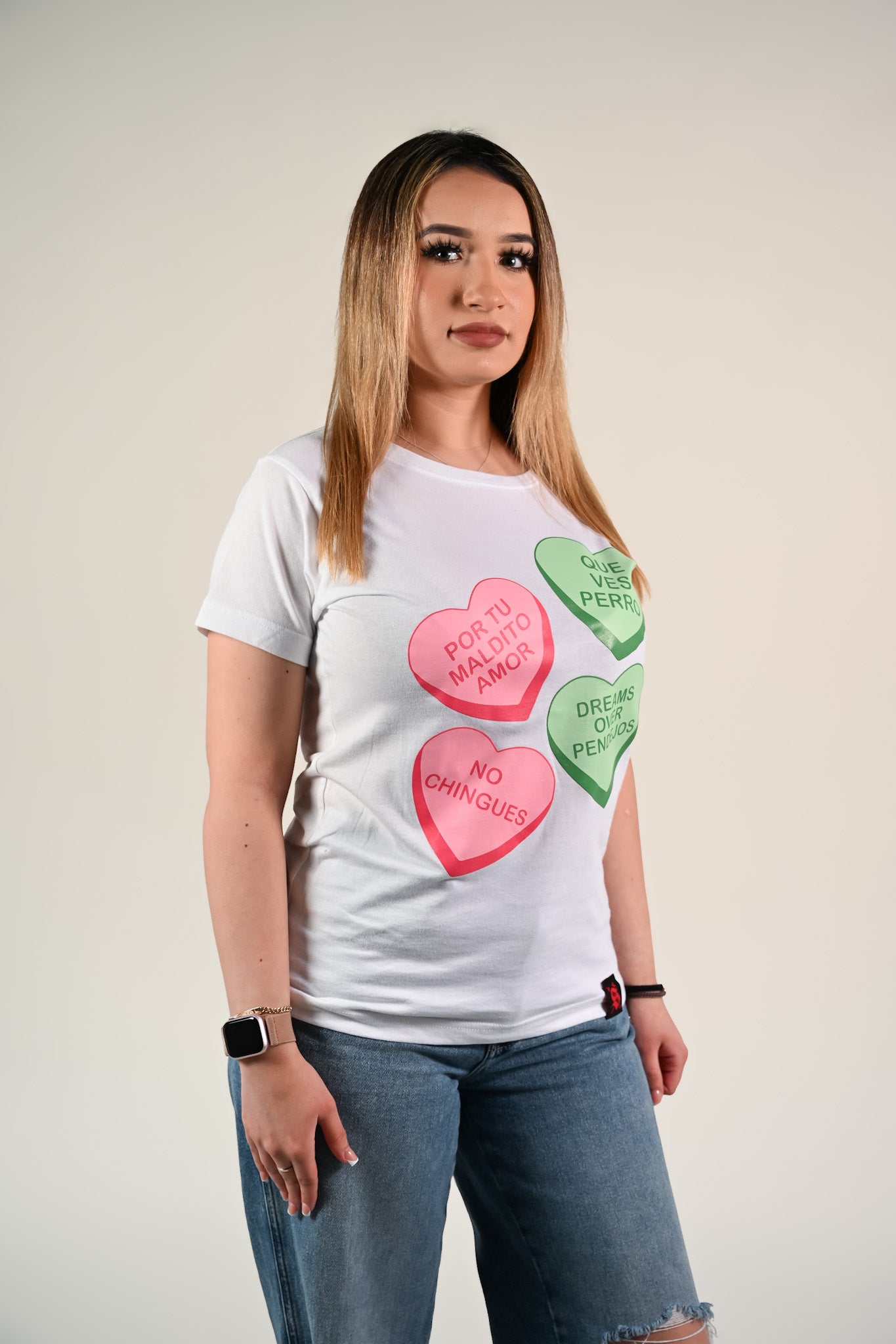 Latina wearing a white t-shirt with colorful Valentine's candy heart-shaped designs on a plain background