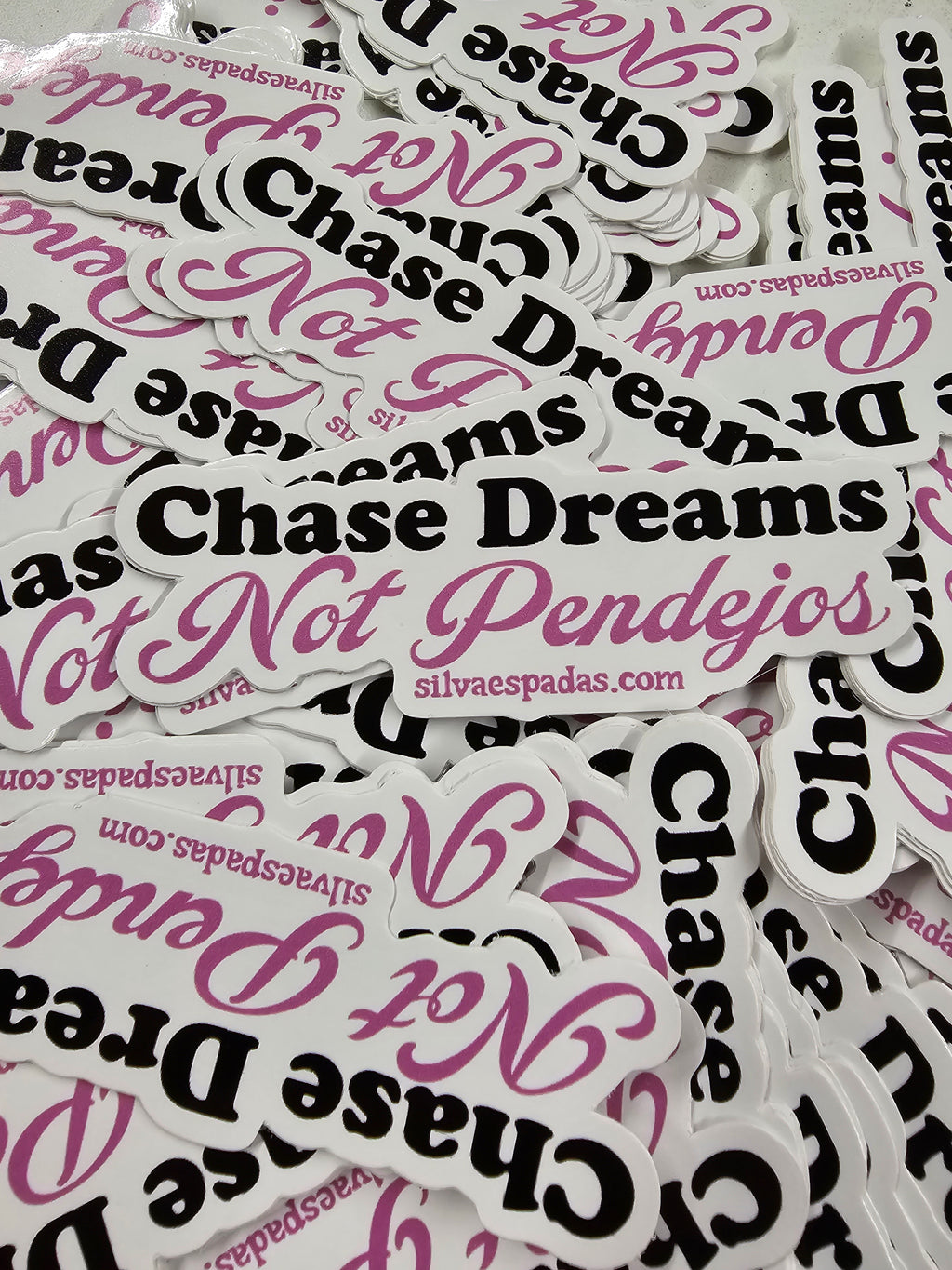 Die-cut stickers of the phrase " Chase Dreams Not Pendejos"