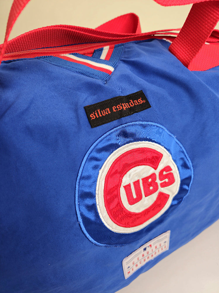 A custom handmade duffle bag made from a Chiago Cubs Genuine Merchendise jacket and heavy canvas, predominantly blue with red and white accents and the Cubs logo.