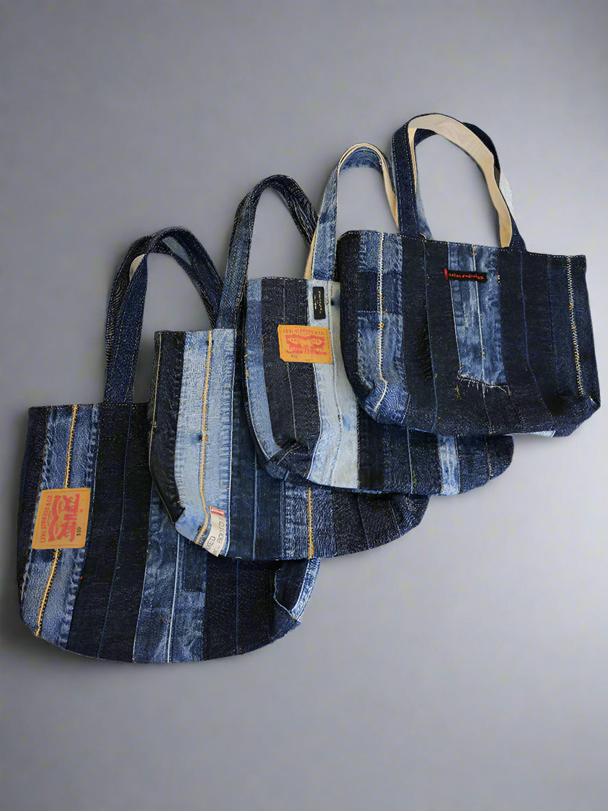 Four handmade disstressed denim tote bags on white background