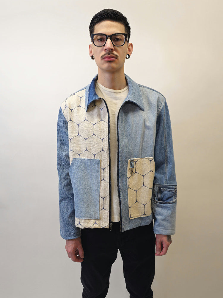 A denim honeycomb jacket with two slanted opening pockets on front panels and a boxy fit. The jacket features a mix of solid denim and honeycomb patterned fabrics.