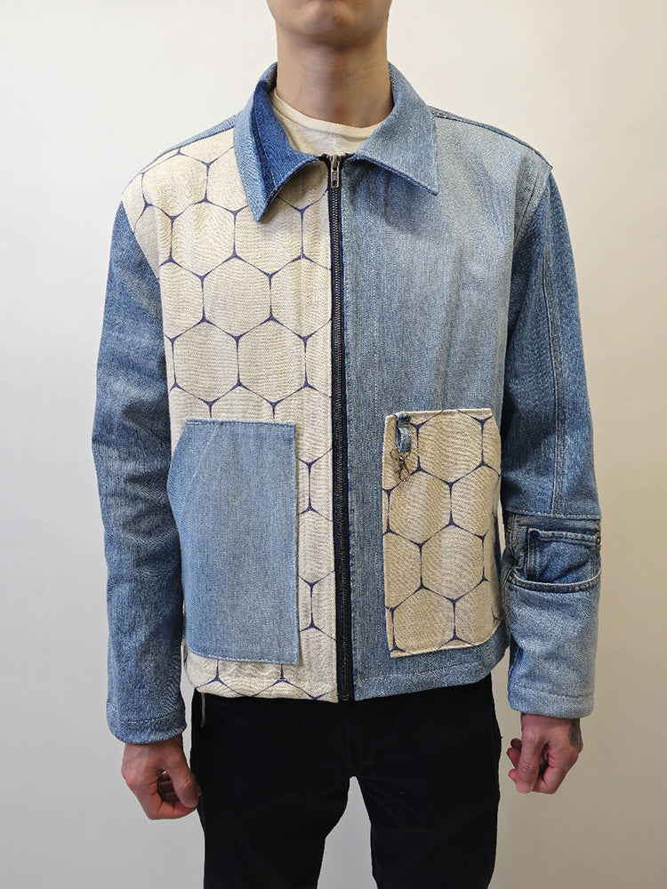 Person wearing A denim honeycomb jacket with two slanted opening pockets on front panels and a boxy fit. The jacket features a mix of solid denim and honeycomb patterned fabrics.
