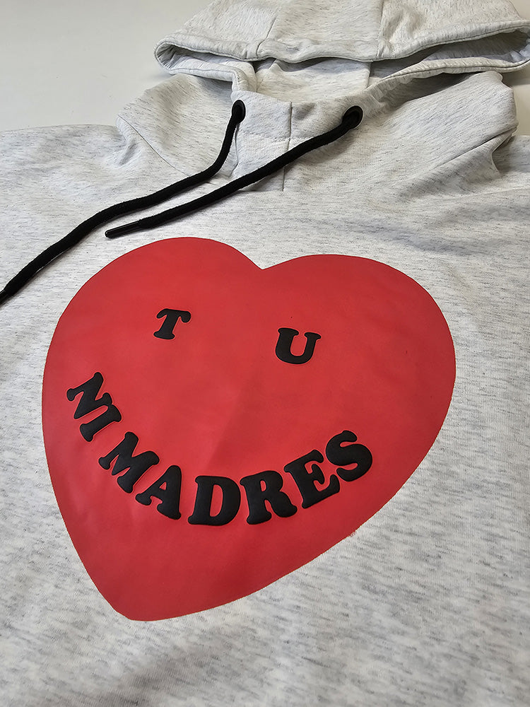 Close up of a hoodie with a red heart and puff print text "Tu ni madres" screen print