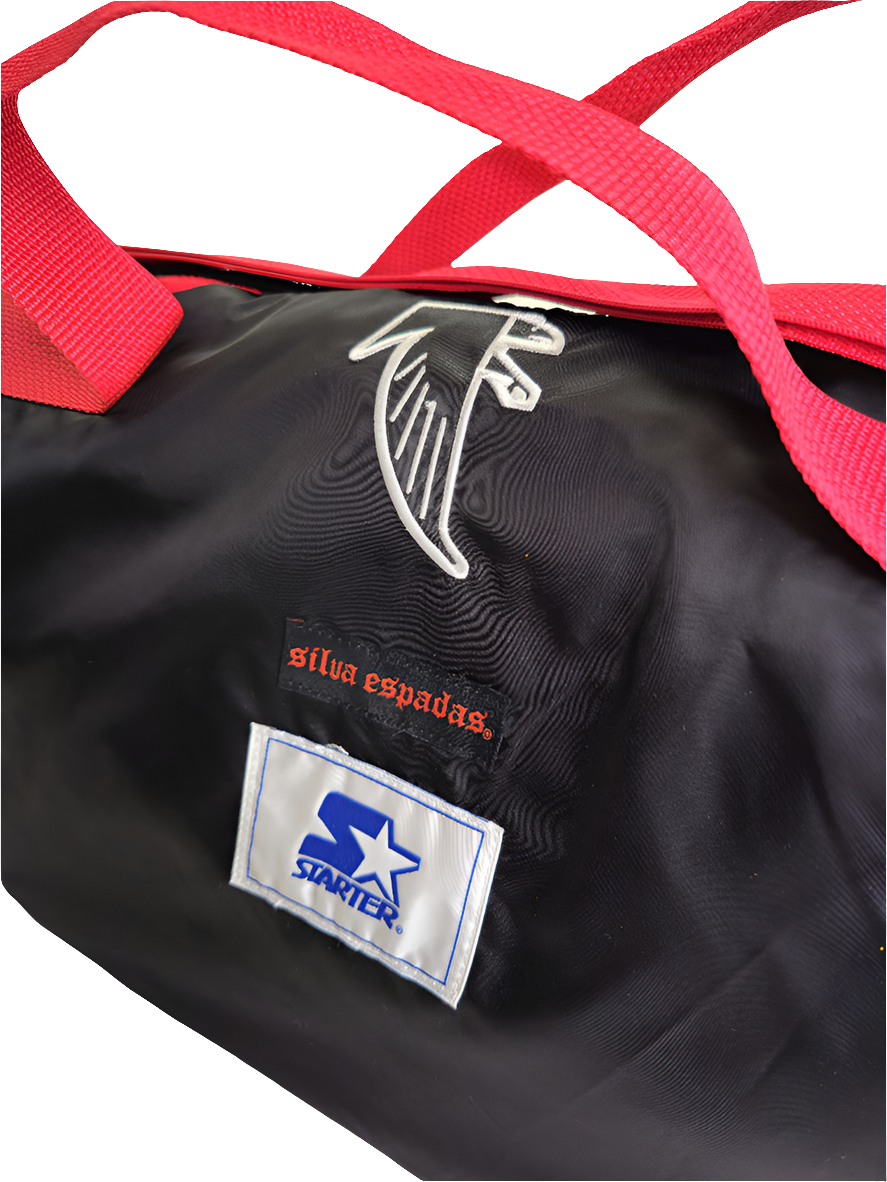 A custom handmade duffle bag made from a Atlanta Falcons Starter jacket and heavy canvas, predominantly black with red accents and the Falcons logo.