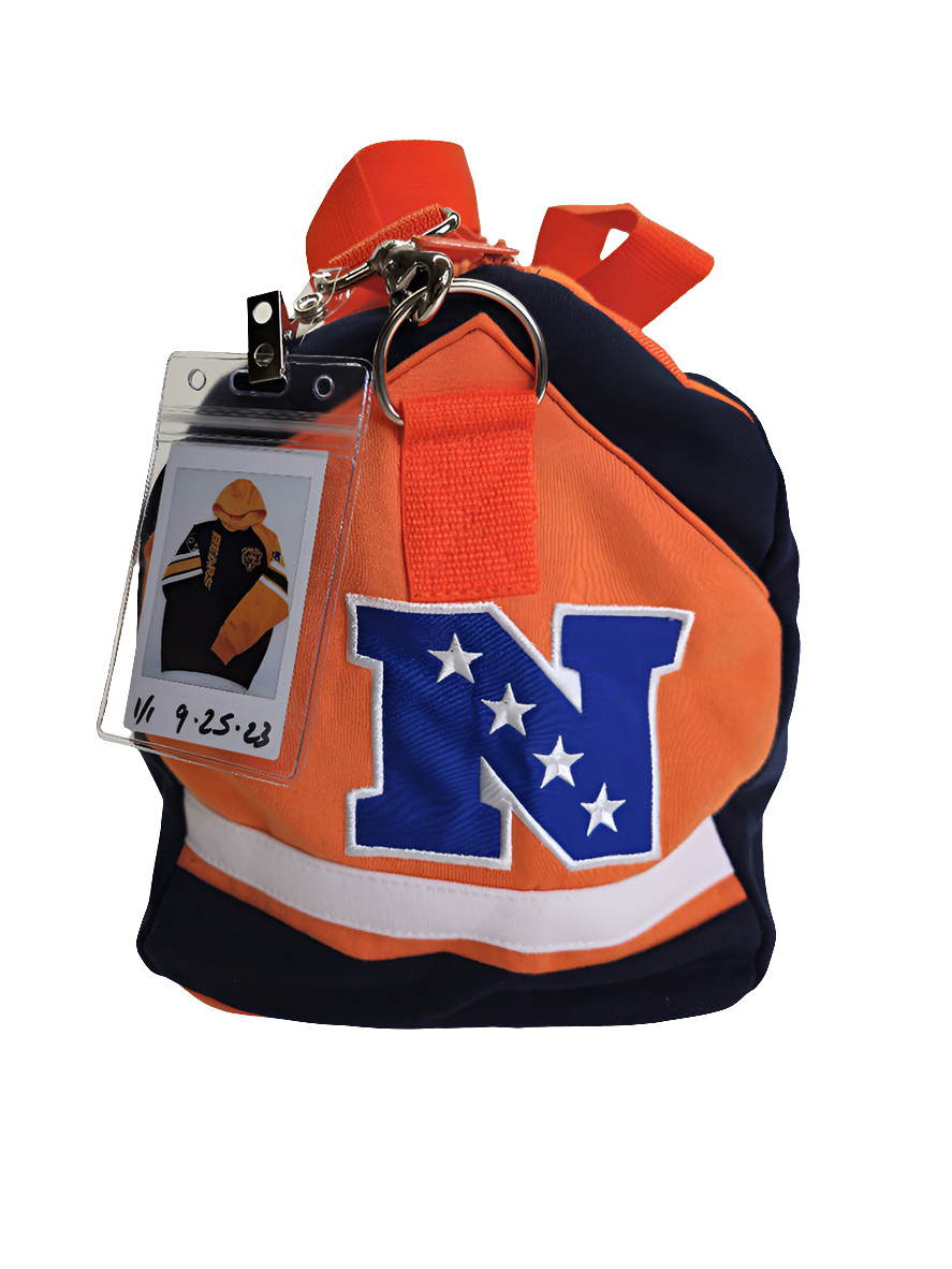 A side view of a navy and orange handmade duffle bag with a Chicago Bears logo and a polaroid picture