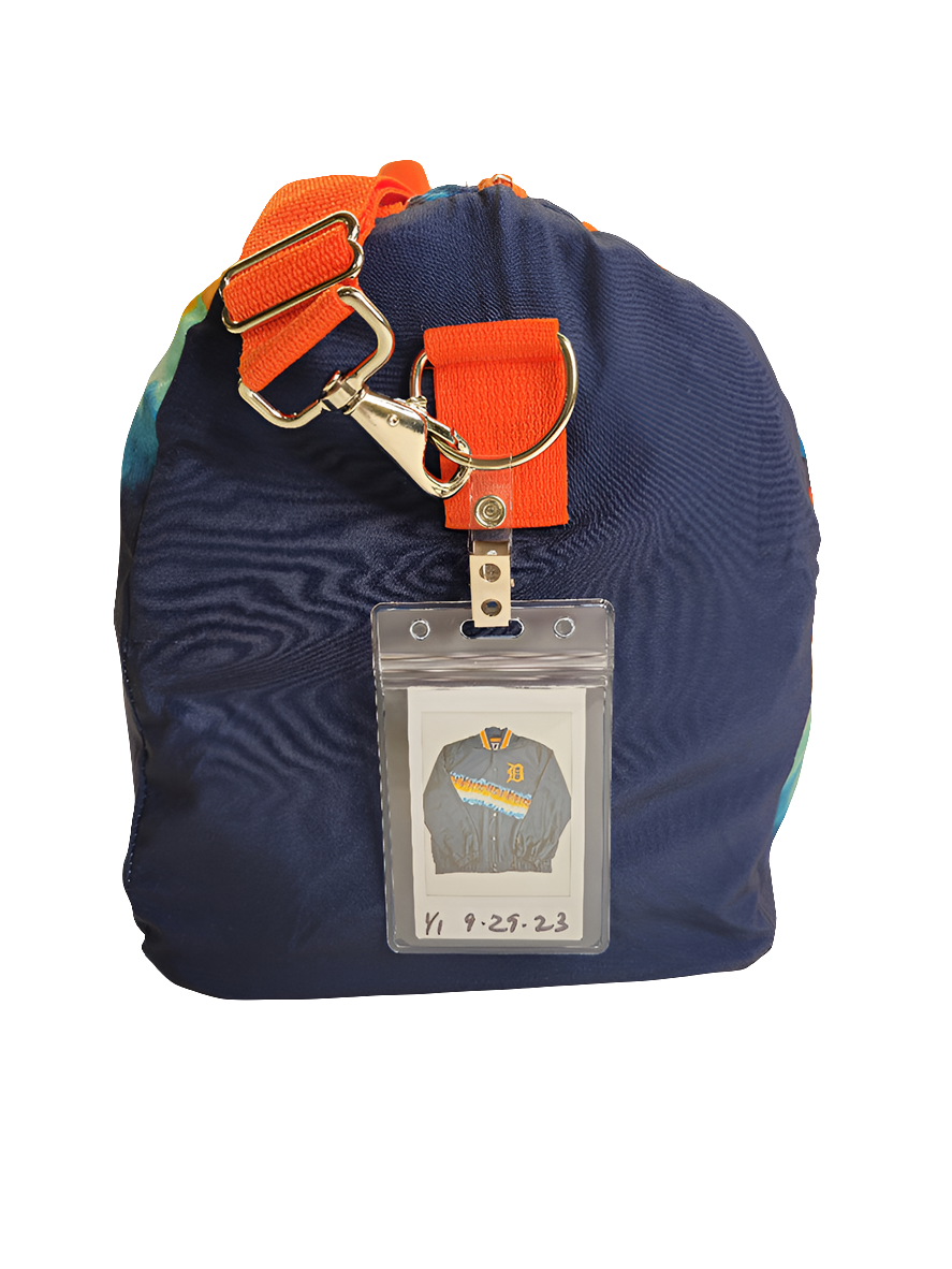 A multicolored handmade duffle bag with Detroit Tigers branding and an orange strap.