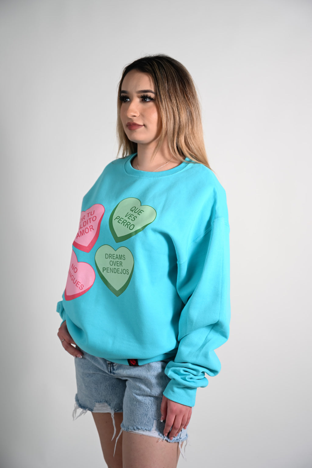 Woman wearing a light blue sweatshirt with heart designs on a plain background