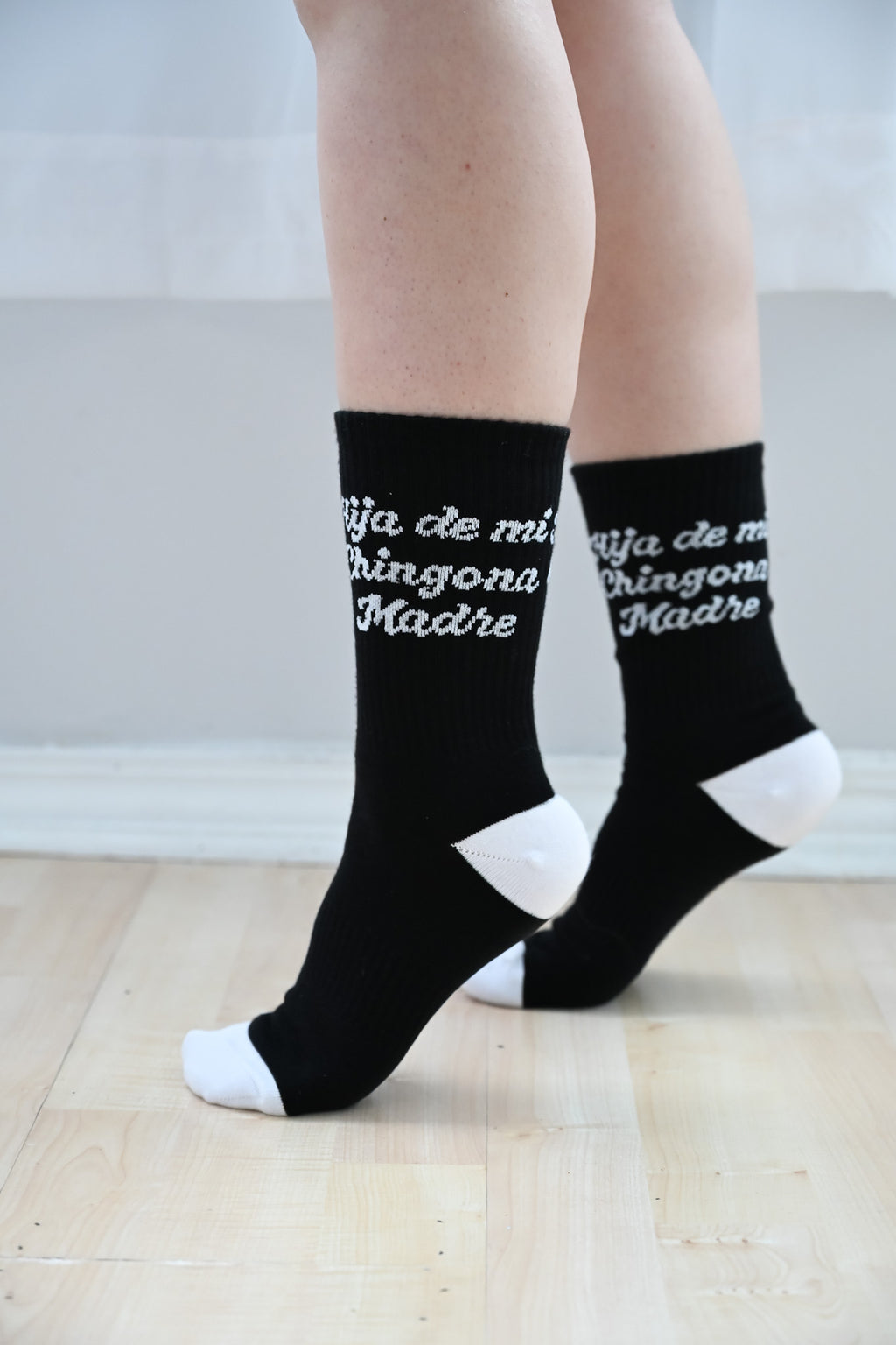 Model wearing black crew length socks with spanish phrase "Hija de mi chingona Madre" by Silva Espadas