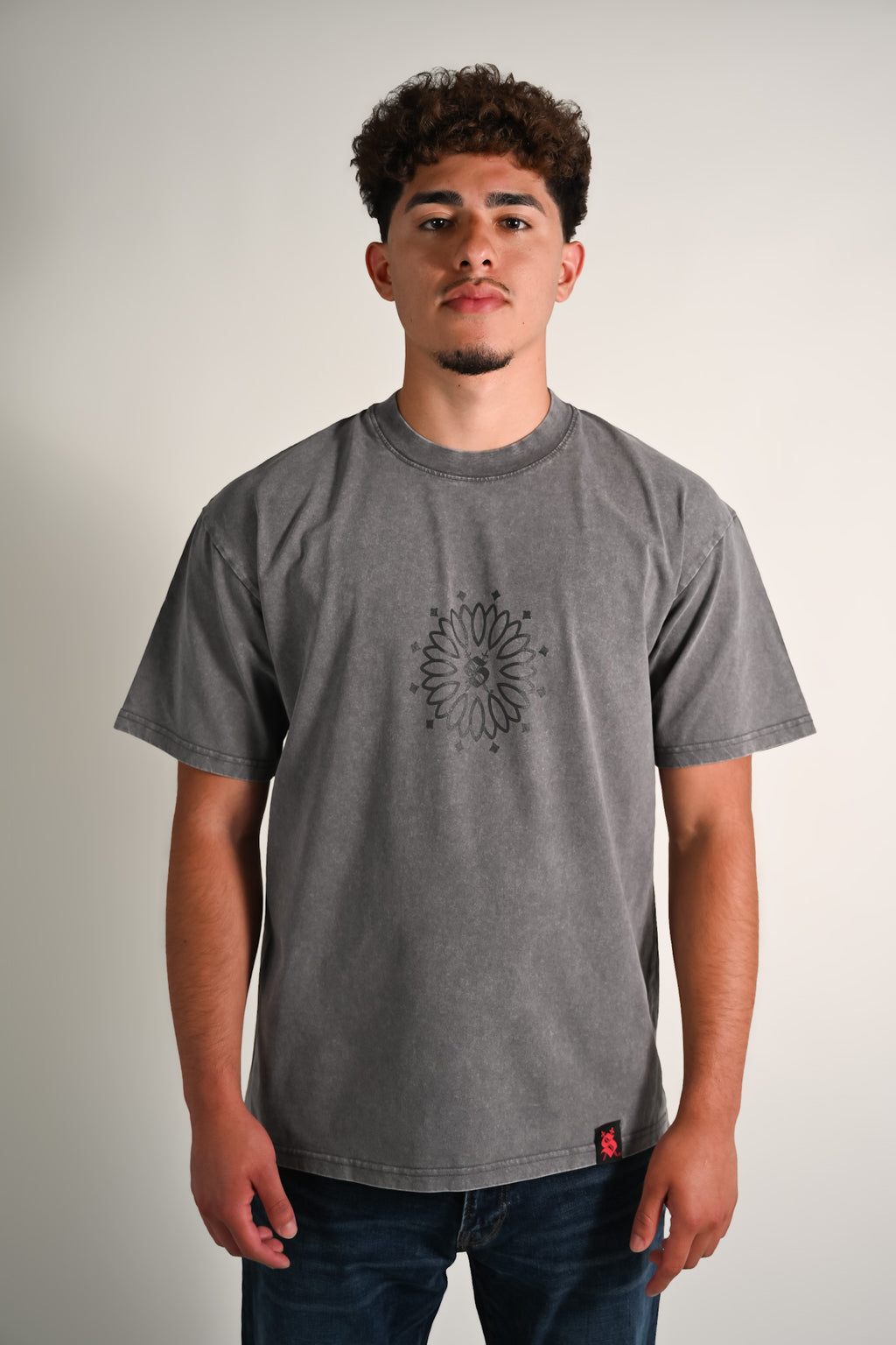 Person wearing a gray t-shirt with a black design on a plain background