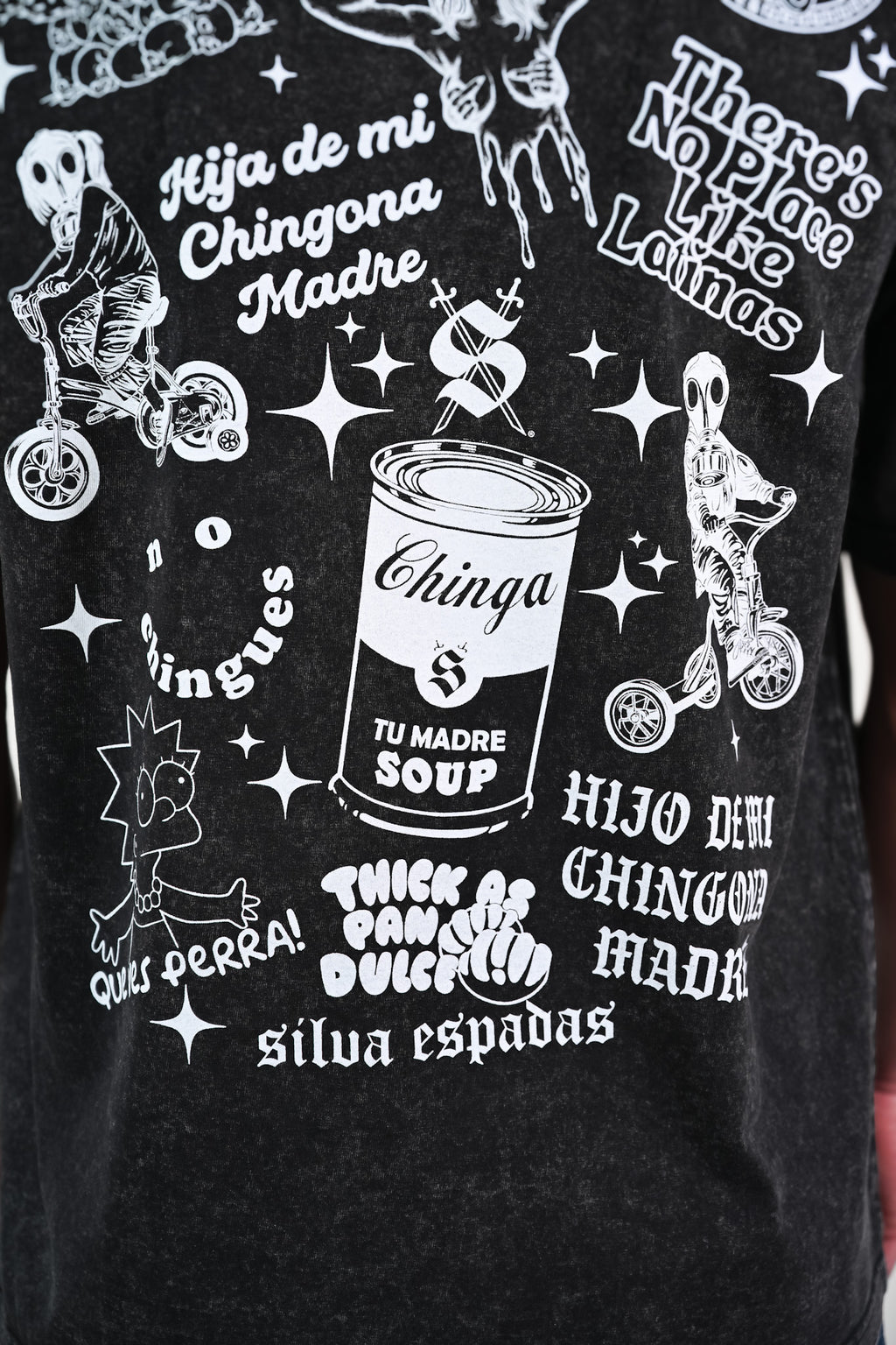 Black t-shirt with Latino-inspired graphic designs and phrases on a black background such as thick as pan dulce and que ves perra