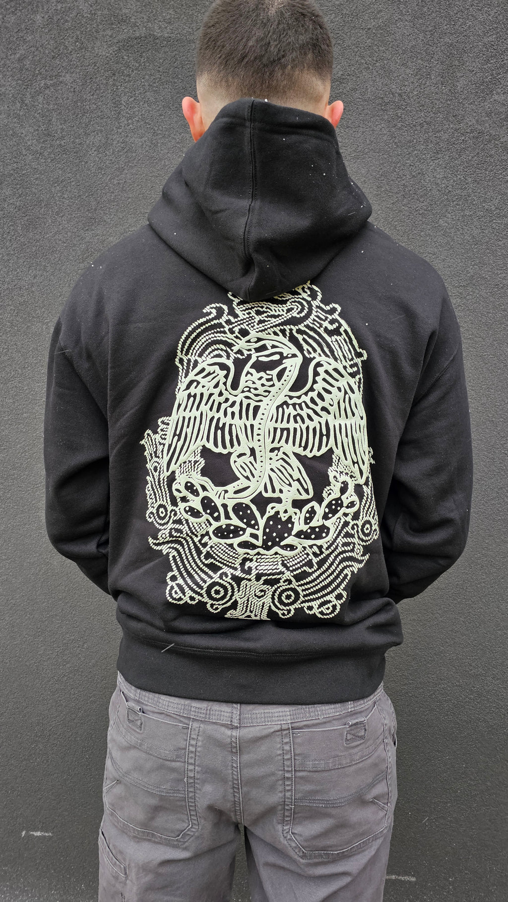 Person wearing a black hoodie with a white graphic design on the back against a gray background