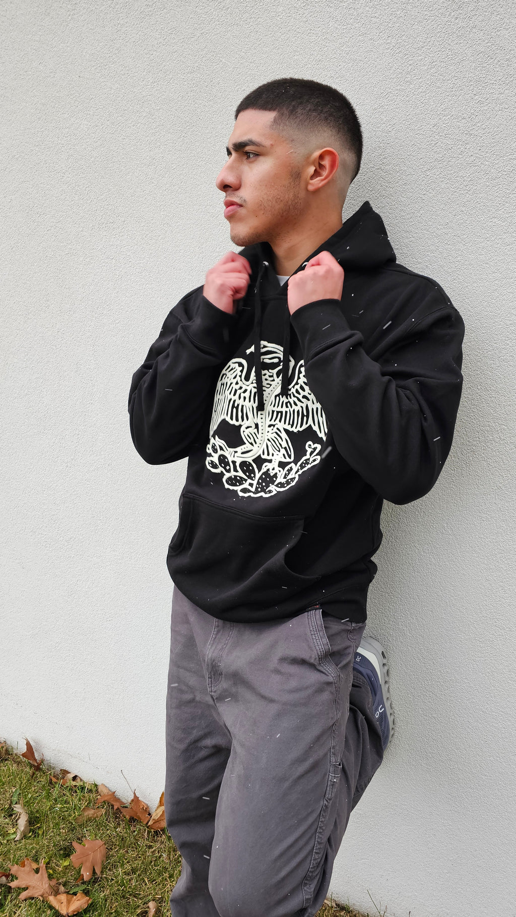 Person wearing a black hoodie with a white graphic design on a light gray background