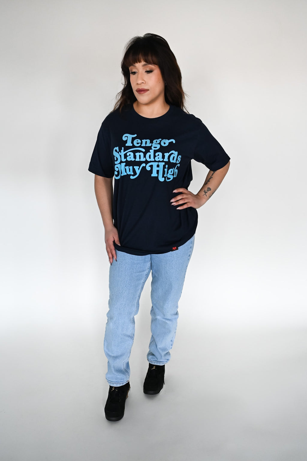Person wearing a unisex navy blue tee against a white backdrop