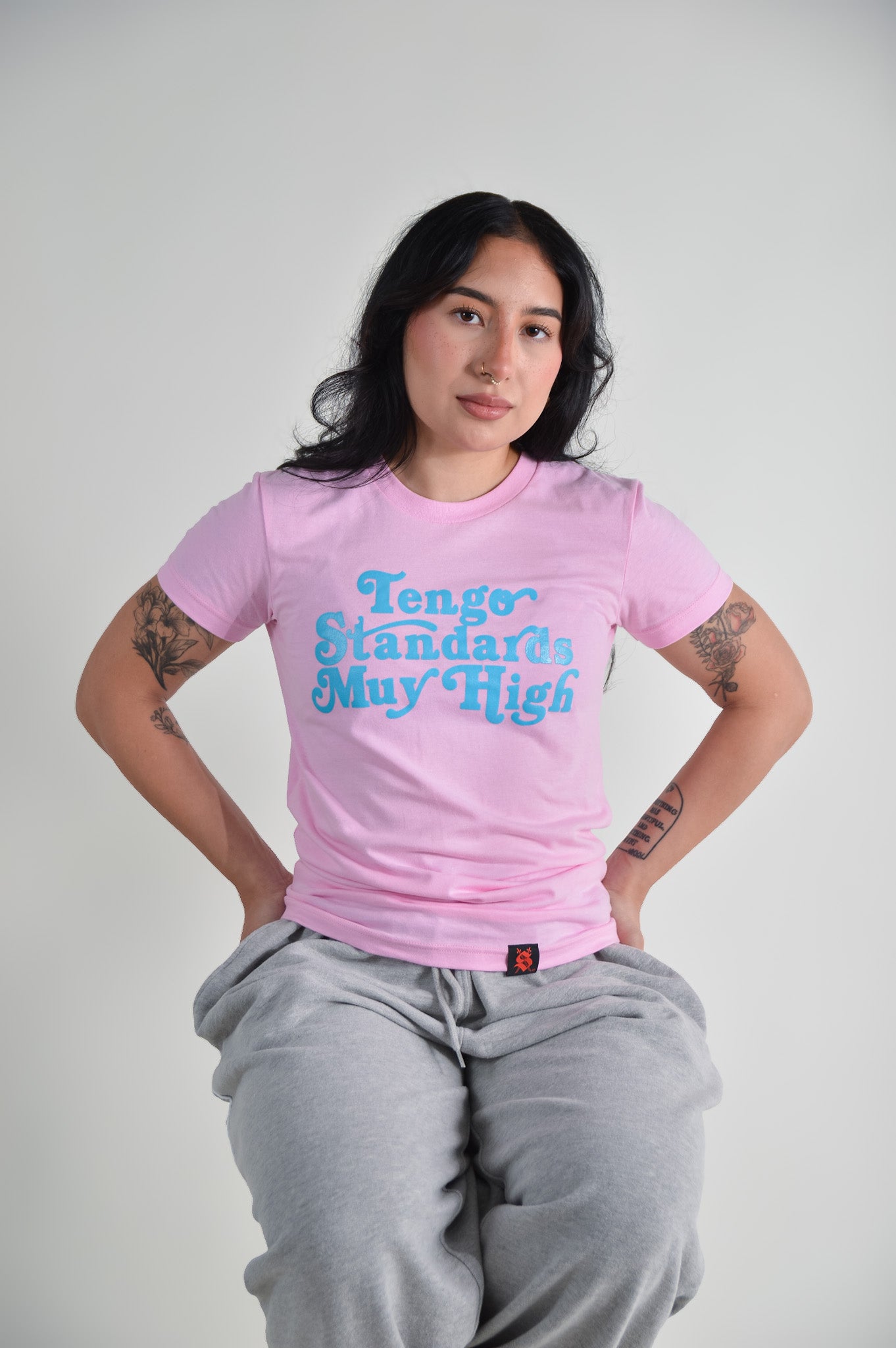 Person wearing a pink t-shirt with blue text on a plain background