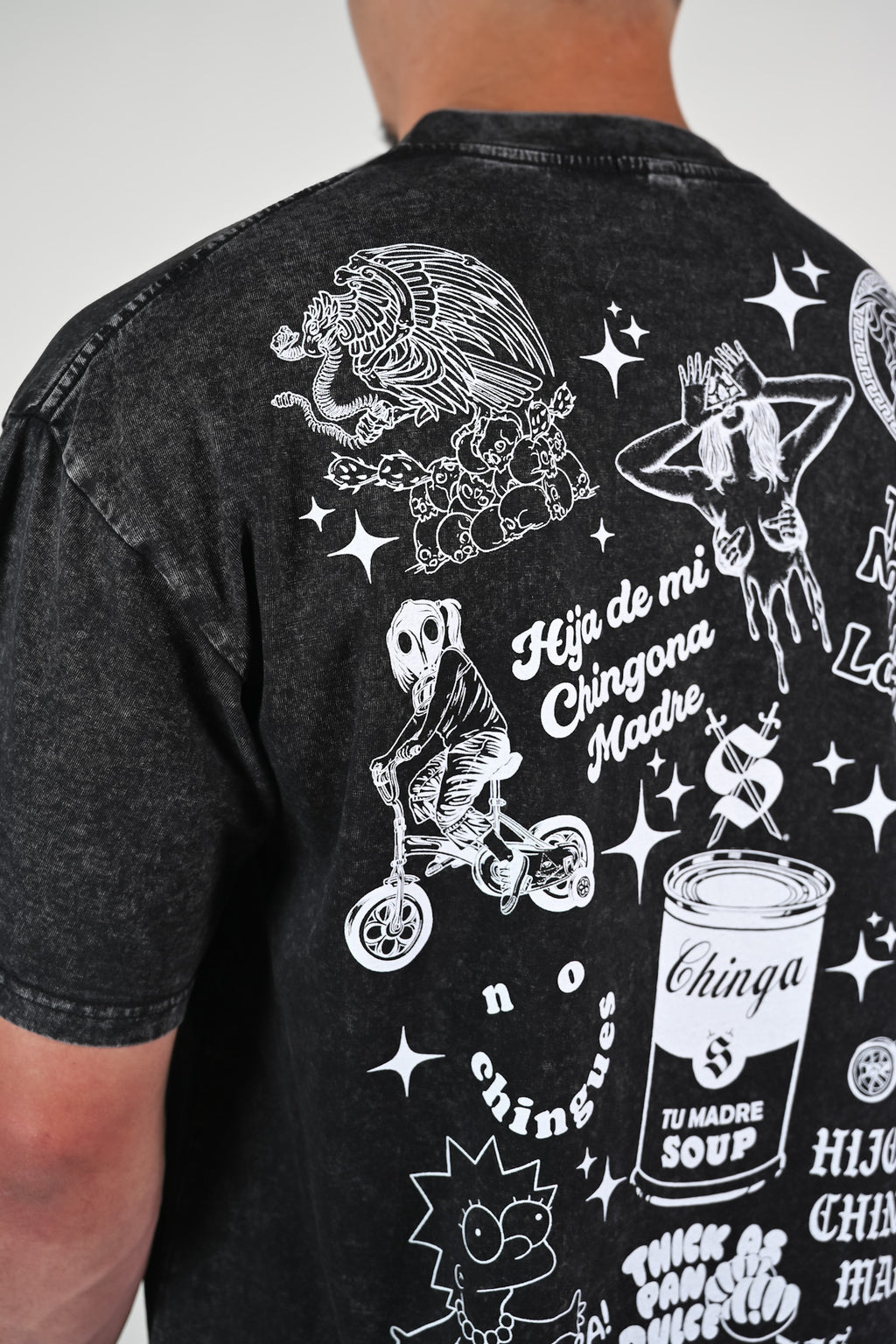 Black t-shirt with white Latino-inspired graphics and phrases such as "no chingues" and text on a plain background