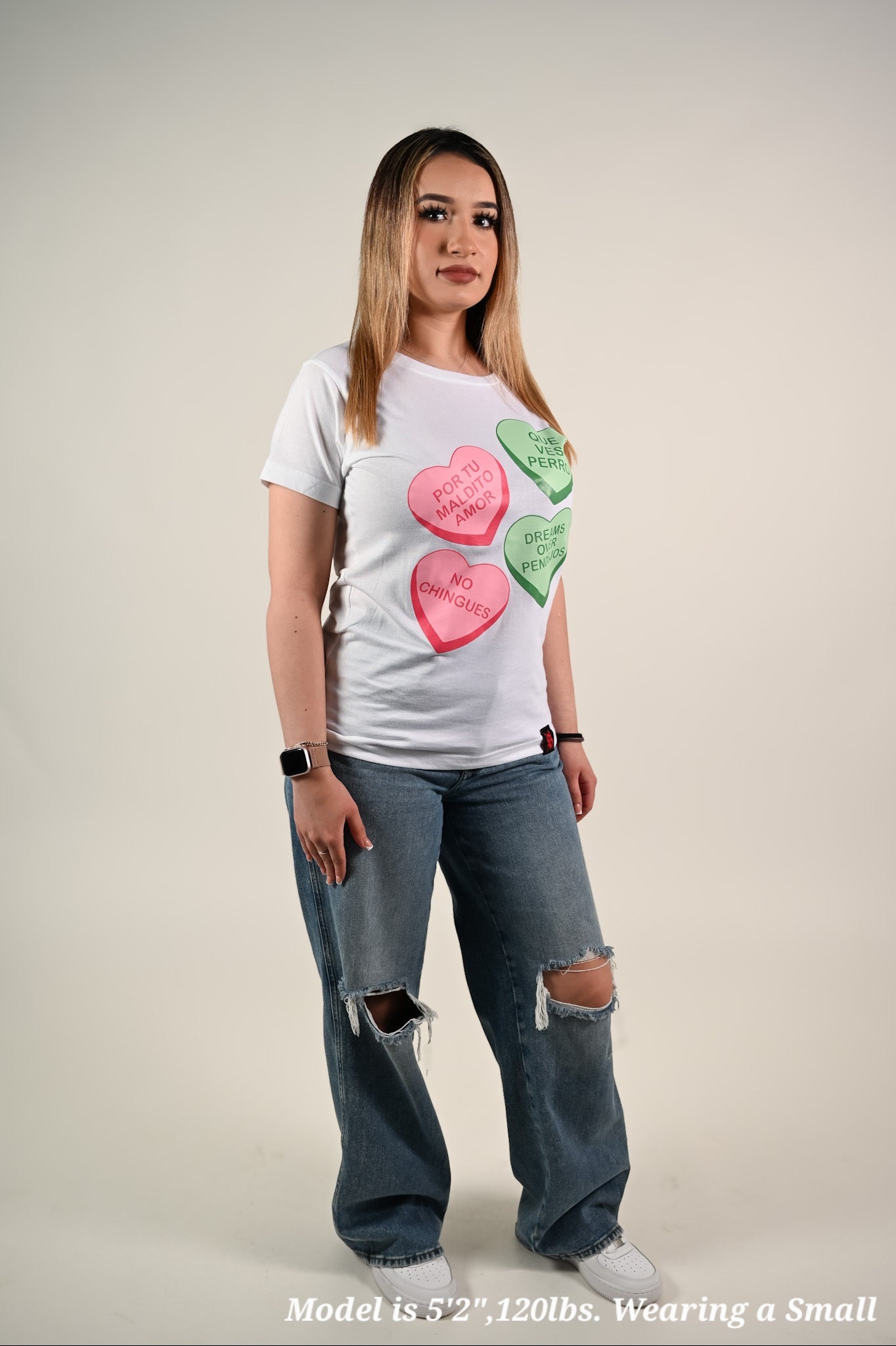 Woman wearing a white t-shirt with colorful heart designs on a plain background