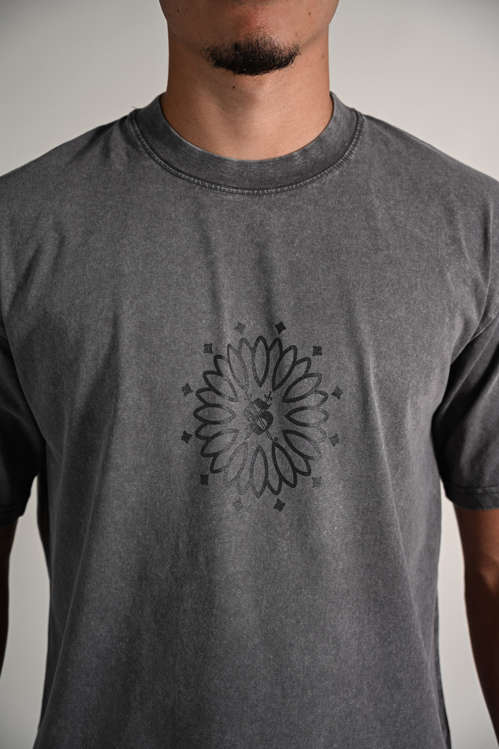 Person wearing a gray t-shirt with a black floral design on a plain background