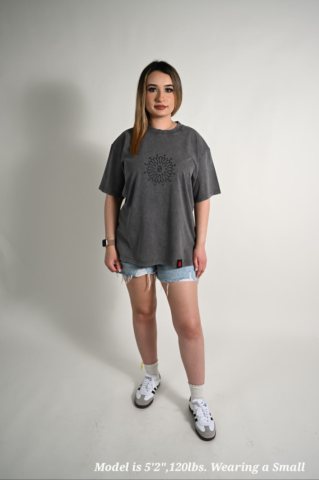 Latina Woman wearing a gray oversized t-shirt with a design on a plain background