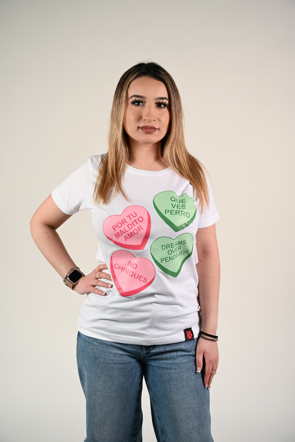 Woman wearing a white t-shirt with colorful heart-shaped text design on a plain background