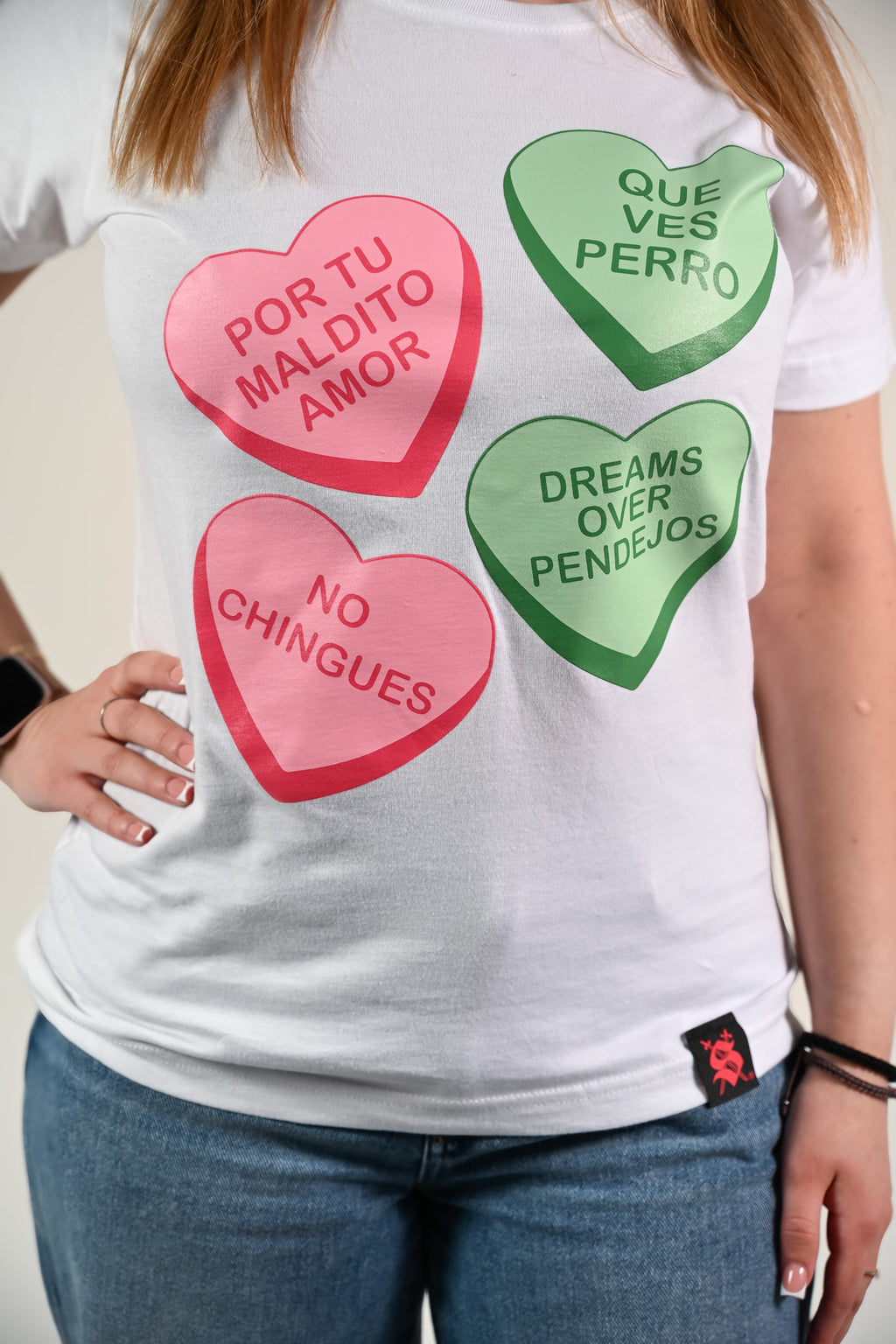 Latina model wearing a white t-shirt with colorful candy heart-shaped graphics and text by Silva Espadas