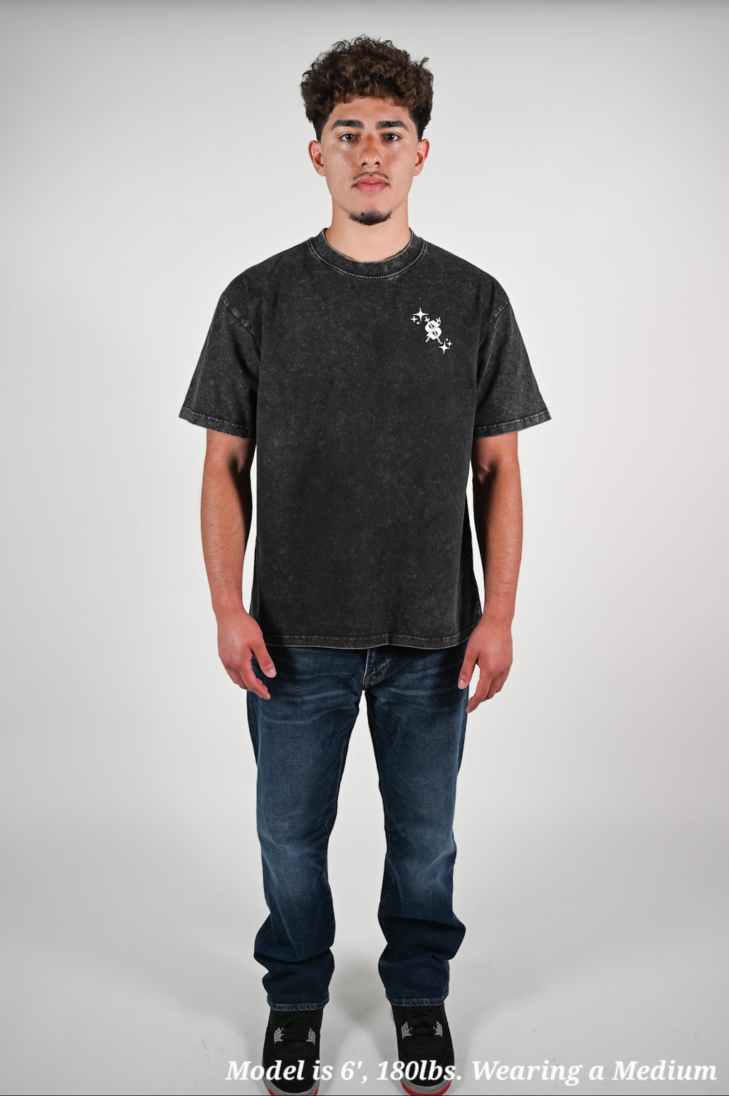Latino model wearing a black t-shirt and jeans on a plain background