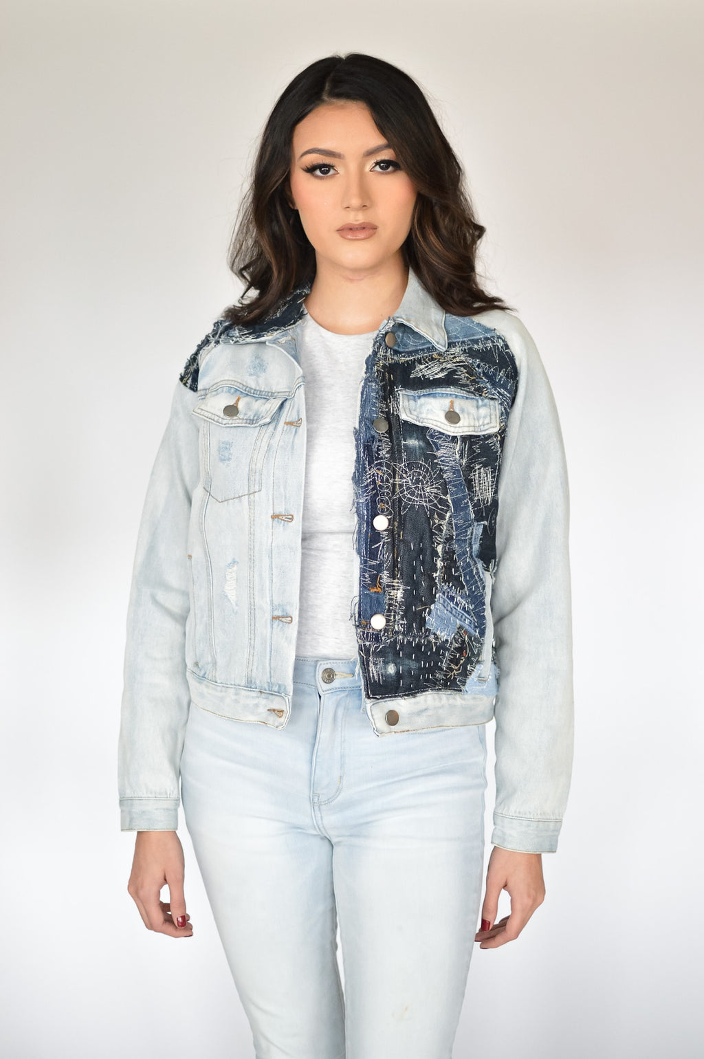 Latina model wearing cropped patchwork denim jacket made from recycled jeans in light and dark blue tones