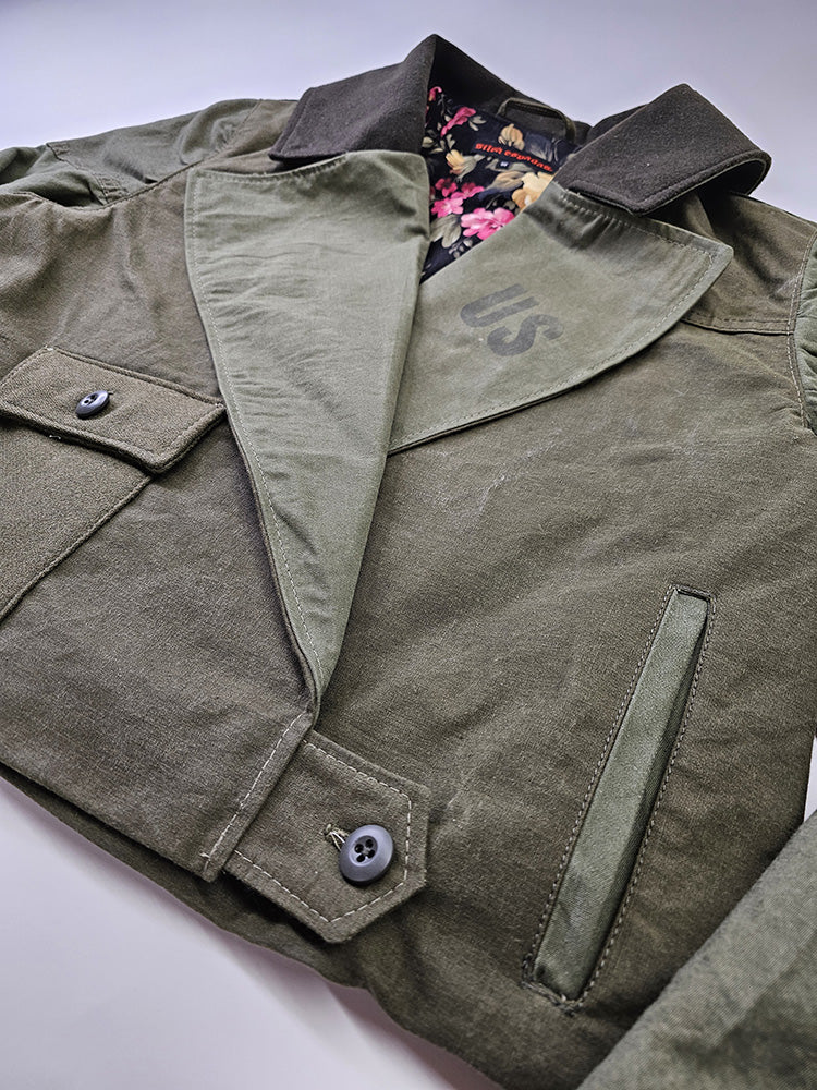 Side shot of cropped olive canvas jacket focusing on flap pocket and welt pocket with sturdy military canvas texture
